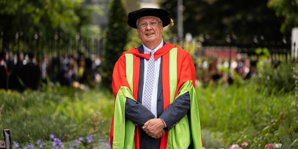 Peter Buckley in red and green graduation gowns