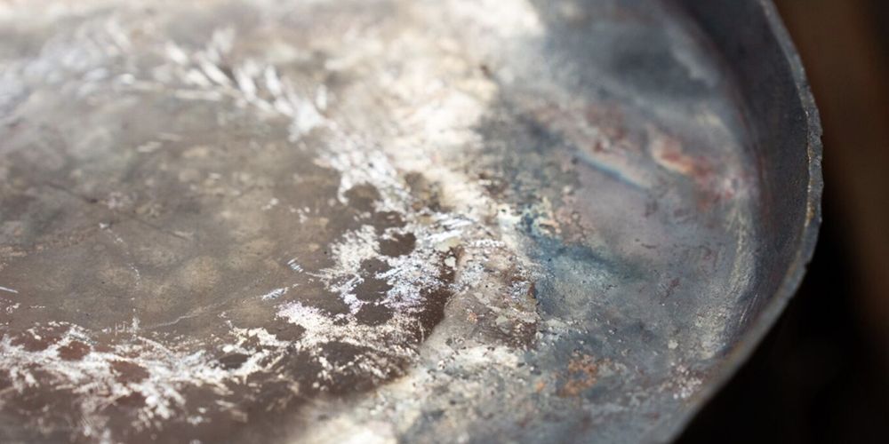 A close up of a flat surface of metal with an interesting patina of marks and colours