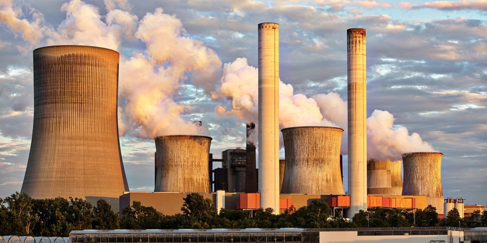 Thick white smoke coming out of chimneys at a power station.