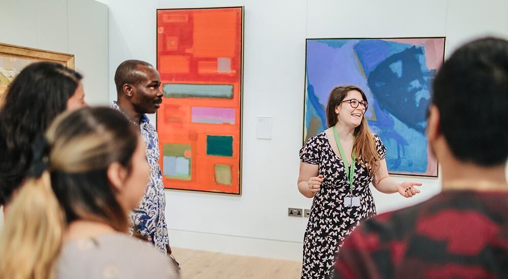 斯坦利和奥黛丽·伯顿画廊，一名画廊工作人员在一幅画前与一群人交谈。
