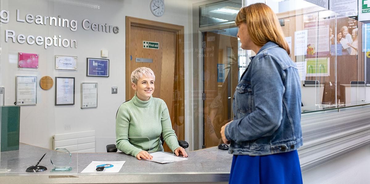 A member of staff talking to a mature student at the Lifelong Learning Centre reception