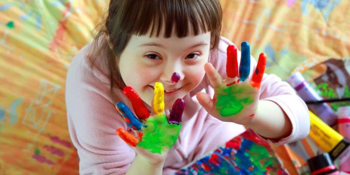 A child painting with their hands and smiling.