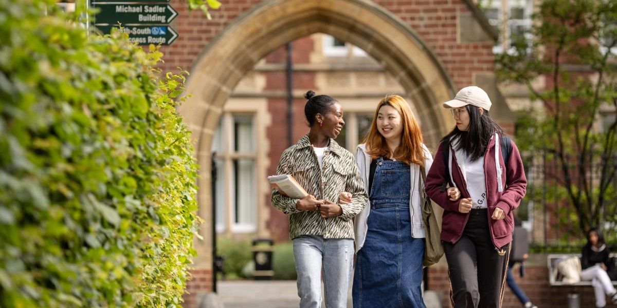 Three students walking and smiling together.