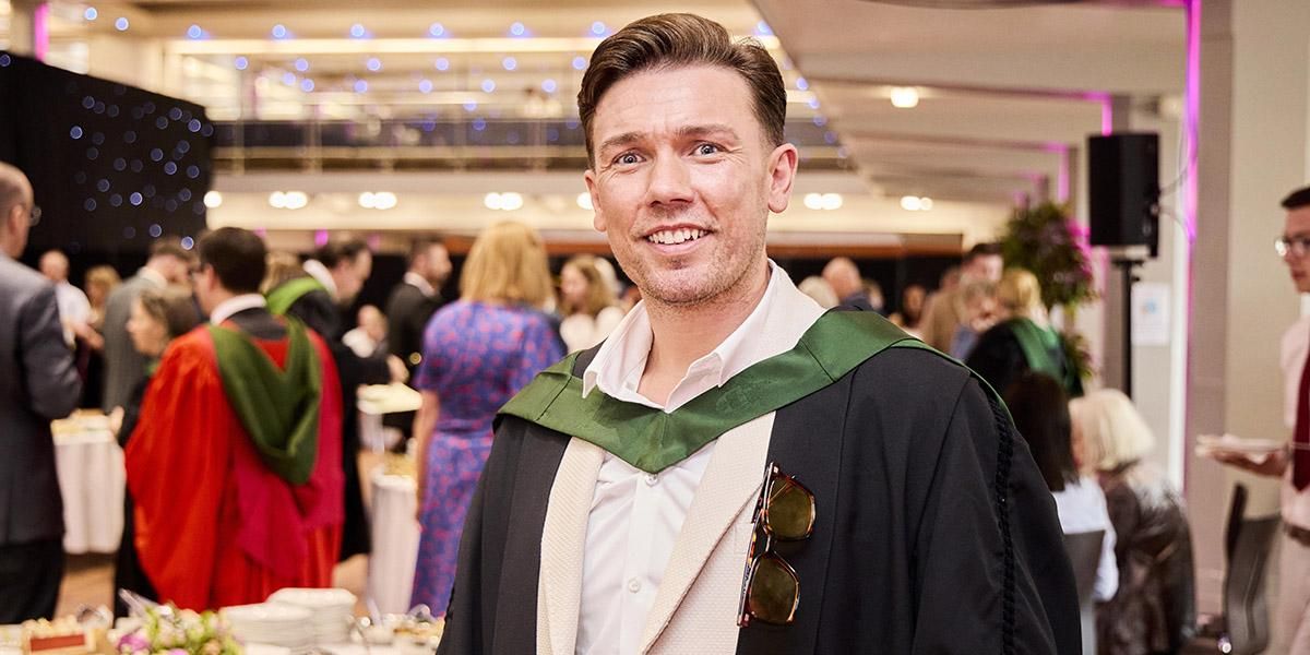 A mature graduate dressed in robes at the Lifelong Learning Centre's graduation ceremony