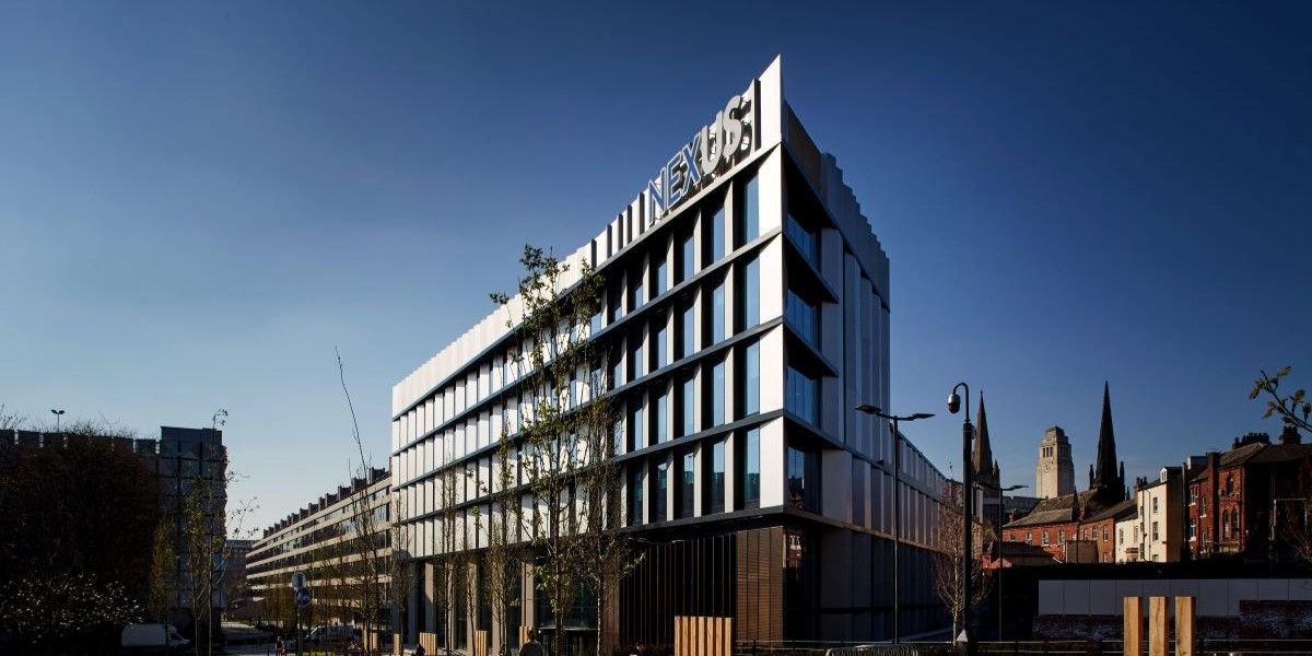 A photograph of the Nexus building taken from an angle. It is a tall, modern, white building with 'Nexus' signage on its face.