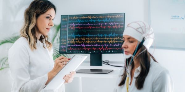 Woman having EEG while female clinician takes notes