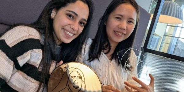 Antara Mulhotra and Yun Ci Liu hold up self portraits on a mirror and a perspex sheet.