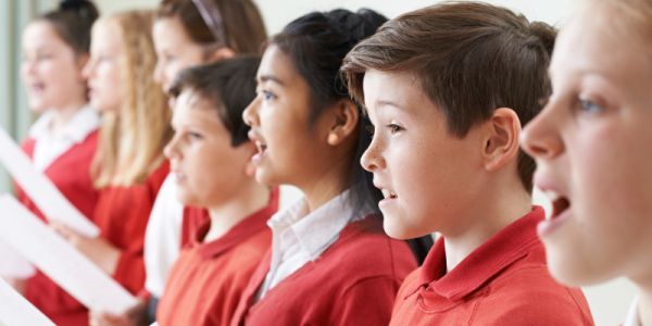 Children in red and white school uniform singing in a choir