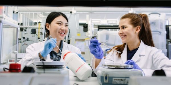 Two researchers wearing white jackets, working in a lab