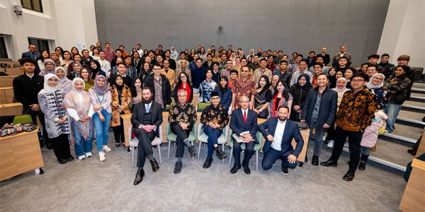 A group photo of the ambassador, panel, delegation and audience all smiling at the camera.