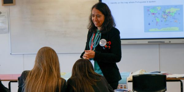 Sofia Martinho delivers a taster session in Portuguese to secondary school pupils at Ossett Academy. A map appears in the background, and in the foreground Sofia smiles at two students.