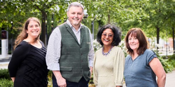 A group shot of the four co directors standing underneath some trees.