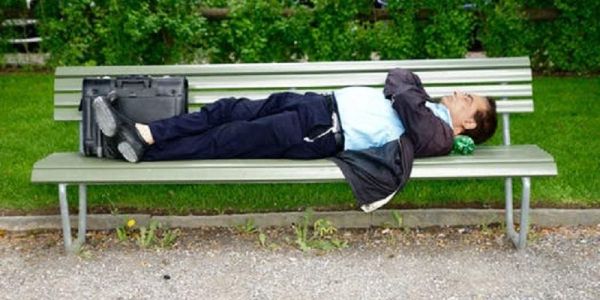 Picture shows a man with briefcase who has fallen asleep on a park bench