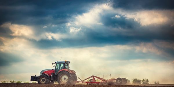 Farmer in a tractor, ploughing a field against stormy backdrop