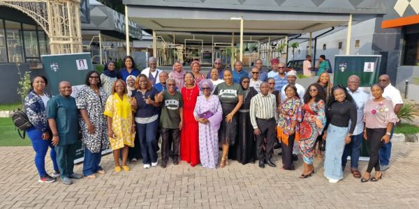 Alumni stand together for a group photo outside a building