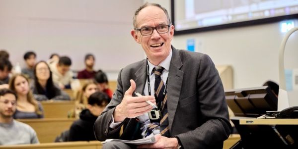 Sir Dave Ramsden delievering a speech in a lecture hall full of students.