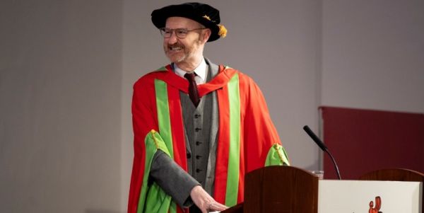 Mark Gatiss in red and green graduation gowns