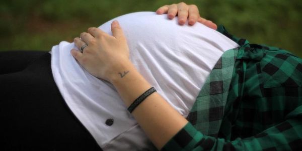 The images shows a pregnant woman lying down feeling her bump.