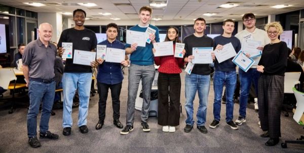 Two module leaders and the winning group of students pose for a photo with their certificates.