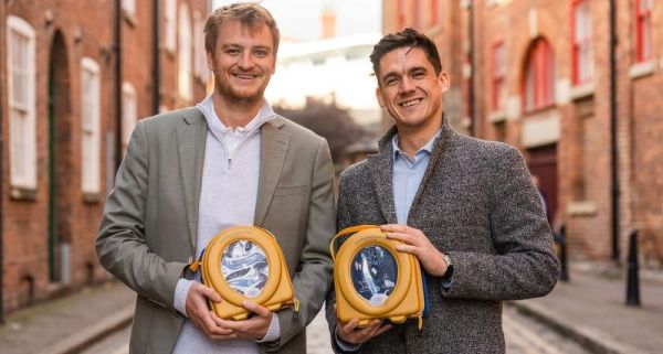 Joe Lawrence and Jonathan Gilbert are stood in the street holding the defib machines they rent out for £1 a day