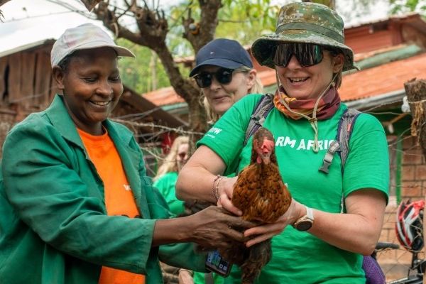 Michelle Morris holding a chicken with a Kenyan Farmer.