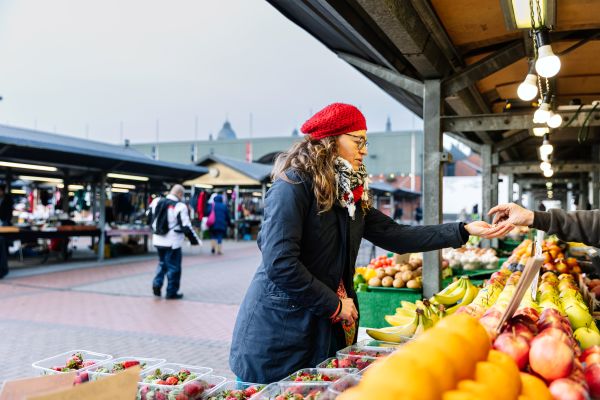 Professor Sara Gonzalez pays for some fruit from a market trader at Leeds Kirkgate Market.