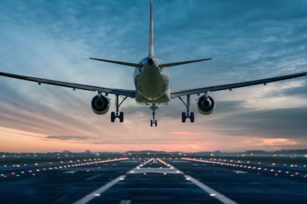 An aeroplane landing on a runway at sunset