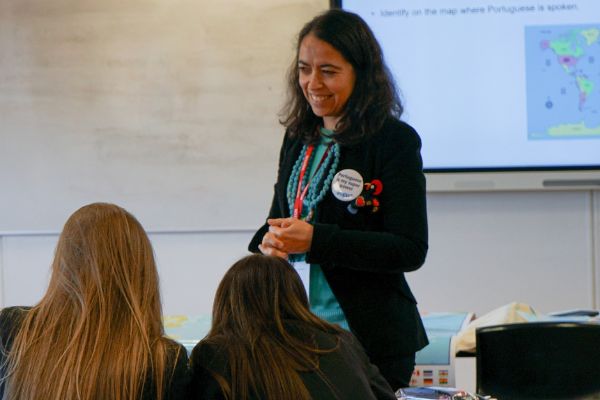 Sofia Martinho delivers a taster session in Portuguese to secondary school pupils at Ossett Academy. A map appears in the background, and in the foreground Sofia smiles at two students.