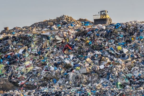 huge pile of waste, with a bulldozer on top