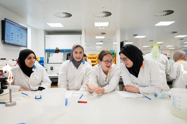 Three students look amazed by a demonstration given by a tutor