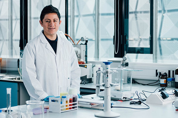 研究生研究员维森特·梅里达（Vicente Merida）身穿白色实验服站在一个工程实验室里。