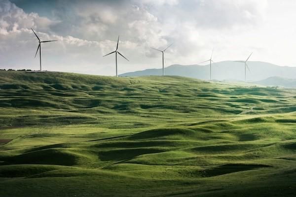 Landscape view of green rolling hills with wind turbines running along the ridge of the hills