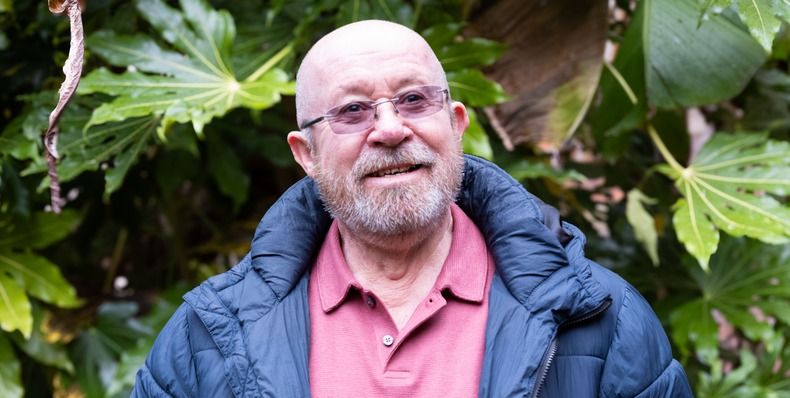 Image of Edward Tayor, standing in front of trees and bushes and smiling at the camera