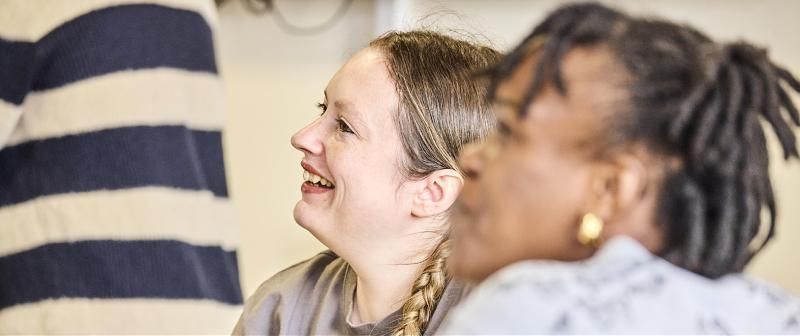 Close up of two mature students in a classroom smiling.