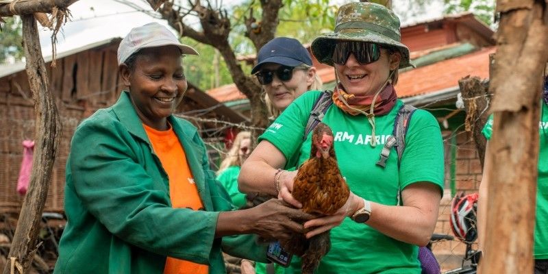 Michelle Morris holding a chicken with a Kenyan Farmer.