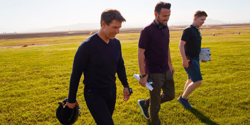 Ben Winston and Tom Cruise walk through a field laughing