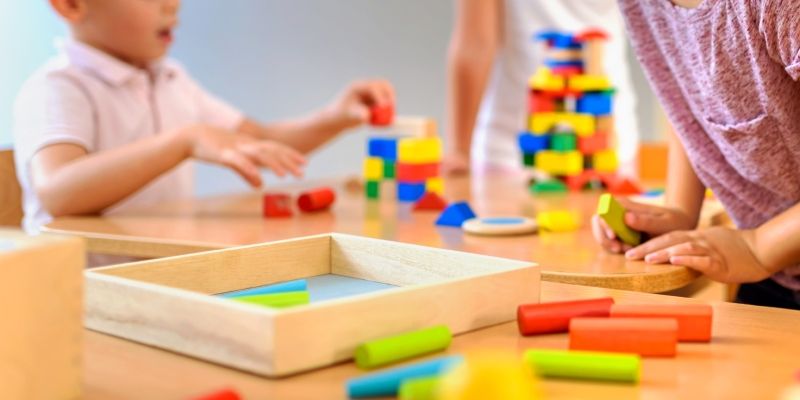 A child and an adult playing with colourful wooden blocks