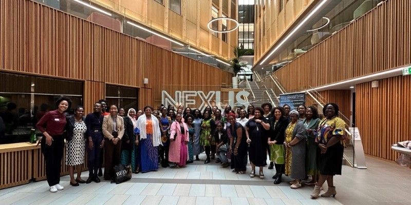 A large group of women from the Black Female Academics Network smiling at the camera in the Nexus foyer.