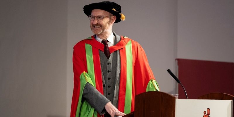 Mark Gatiss in red and green graduation gowns