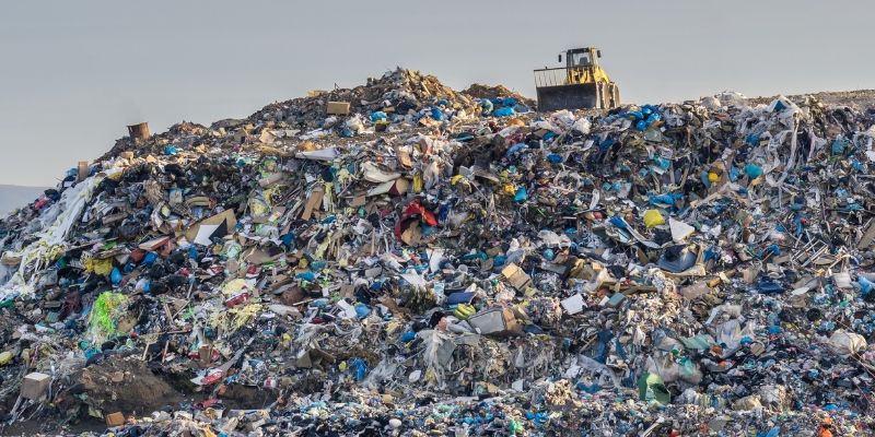 huge pile of waste, with a bulldozer on top