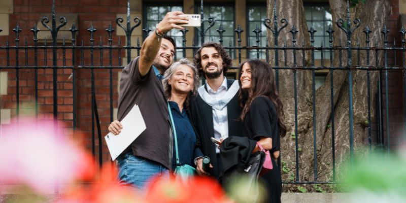 A graduate smiles for the camera as a group selfie is taken.