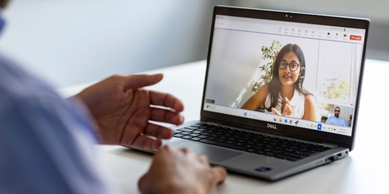 A person sat in front of a laptop, with video call showing on the screen.