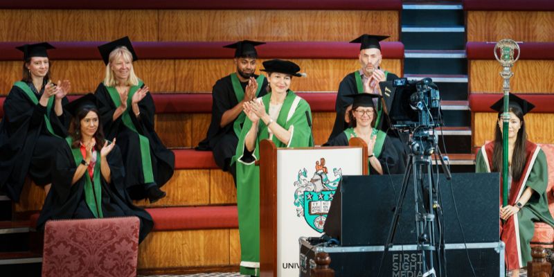 University of Leeds staff taking part in an online graduation ceremony. They are wearing graduation robes and applauding.