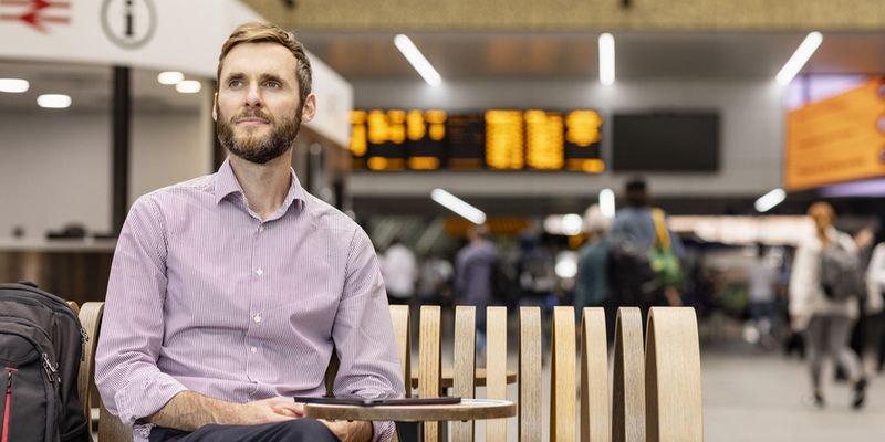 An online student in a smart shirt sitting in Leeds train station