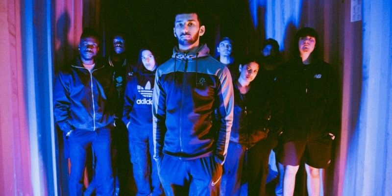 A group of 8 people stood in a shipping container looking at the camera.