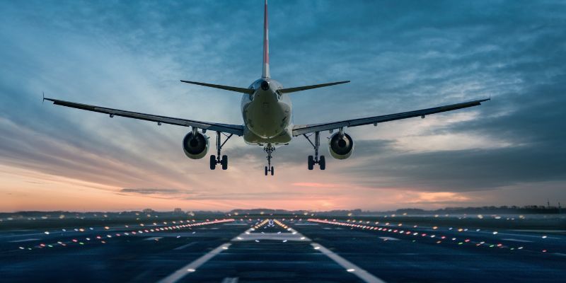 an aeroplane landing on a runway at sunset