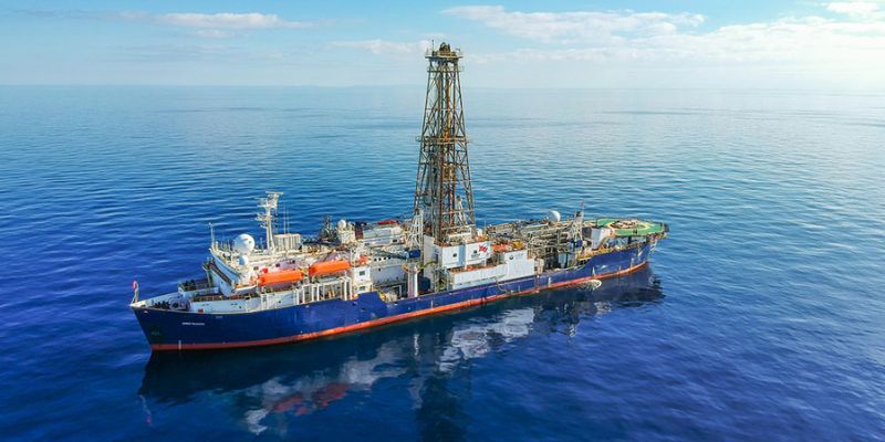 The ocean drilling vessel JOIDES Resolution is photographed at sea.