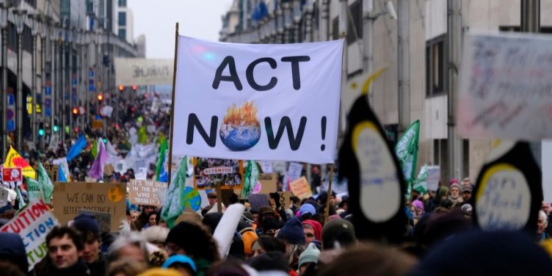 Crowd hold 'ACT NOW' sign at climate protest for COP28