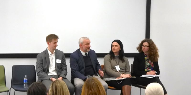 Four panellists sit in a row. From left to right: Patrick Reynolds, Peter O’Brien, Rosie Armitage and Carrie Heitmeyer