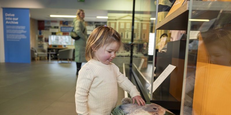 A small child looking at a printed cushion